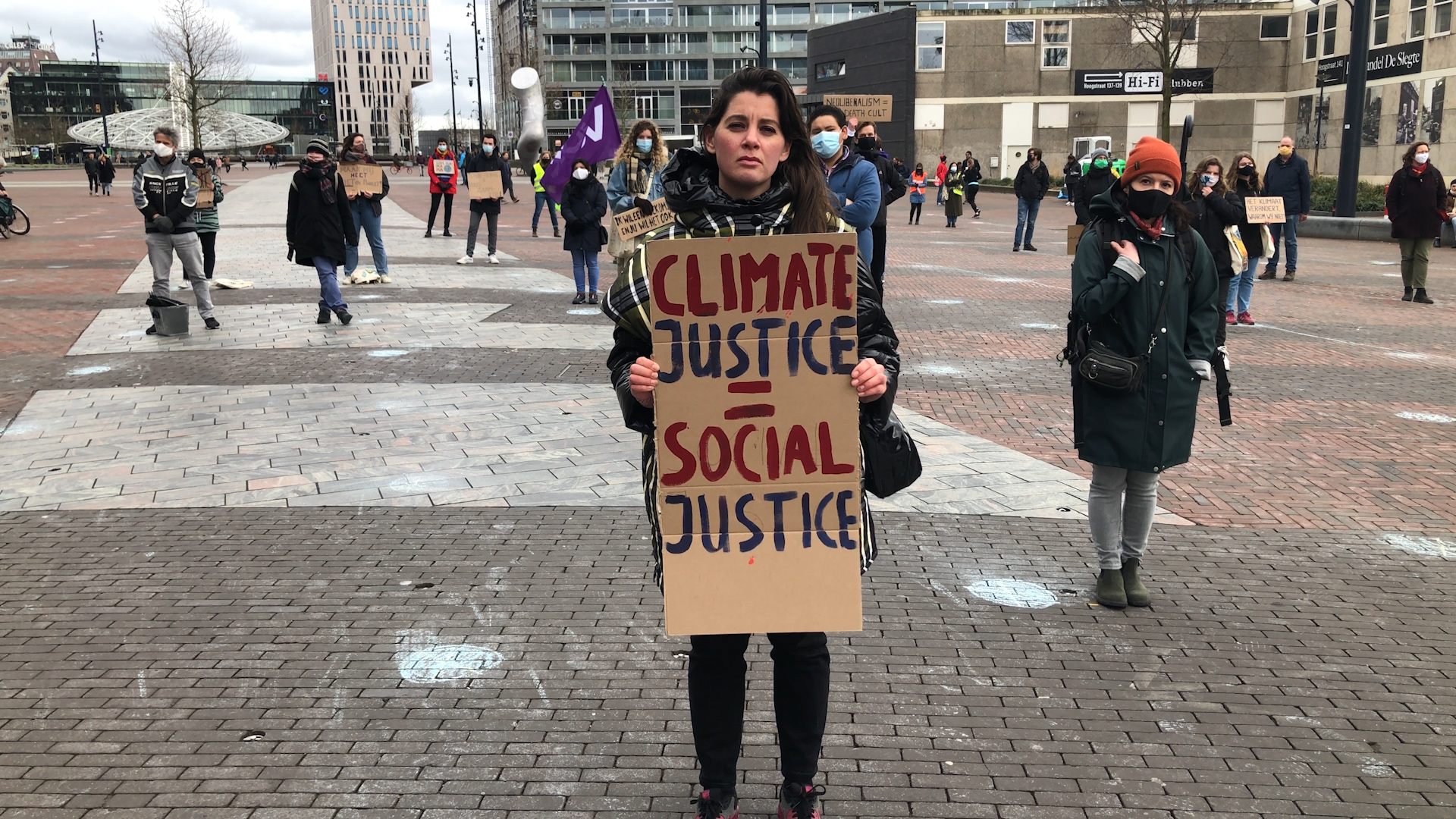 Reporter Cathelijne houdt een bord met tekst vast tijdens het klimaatalarm in Rotterdam